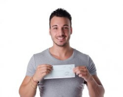 אדם צעיר מחזיק צ'ק הלוואה שקיבל מהאגודה הישראלית להלוואות ללא ריבית