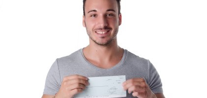 אדם צעיר מחזיק צ'ק הלוואה שקיבל מהאגודה הישראלית להלוואות ללא ריבית